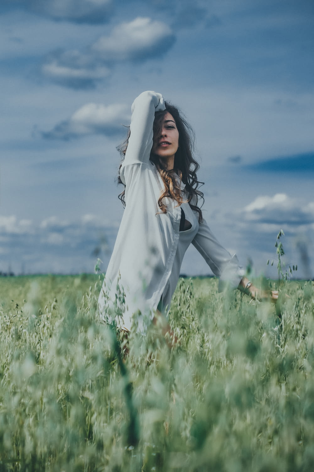 woman in white long sleeve dress standing on green grass field under blue sky during daytime