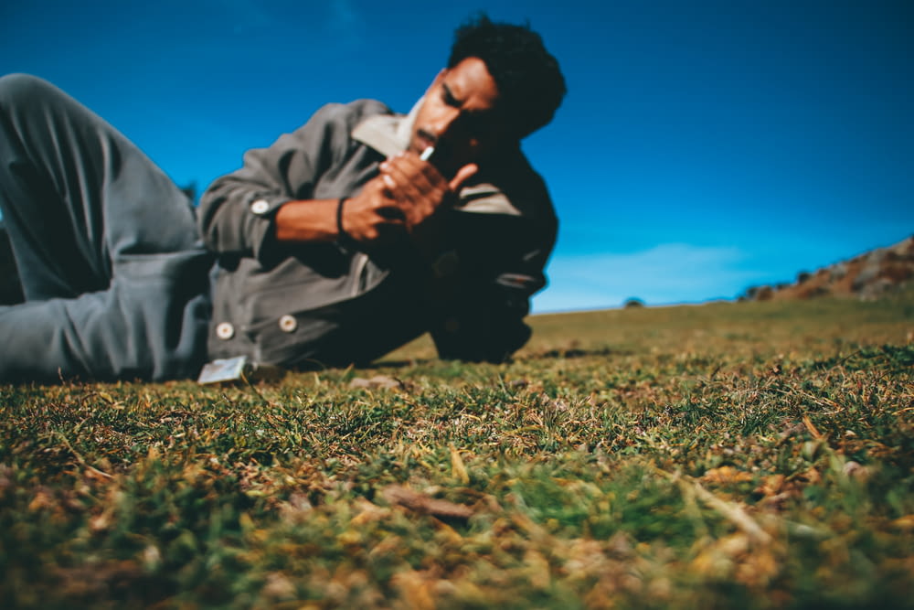 man in gray jacket sitting on green grass field during daytime