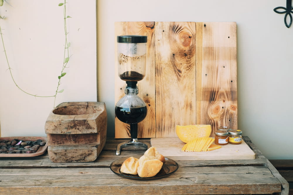 bread on brown wooden chopping board beside black and clear glass vase