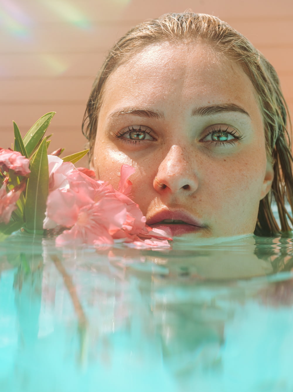 woman in water with pink flower petals