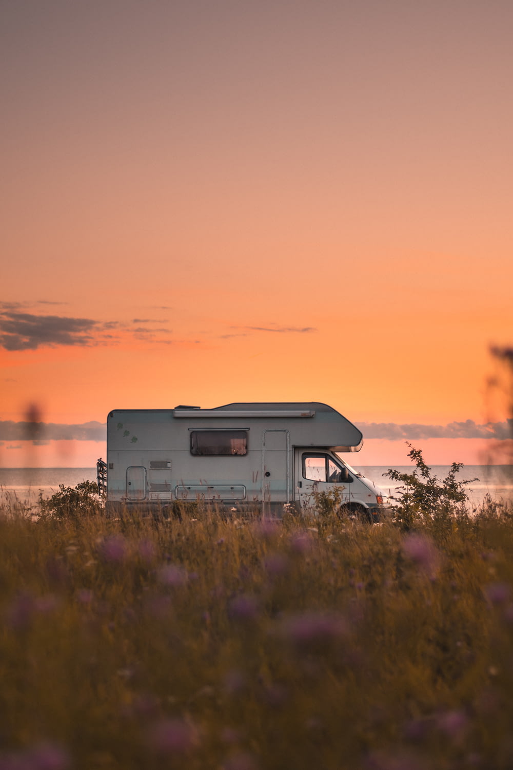 white and gray rv on green grass field during sunset