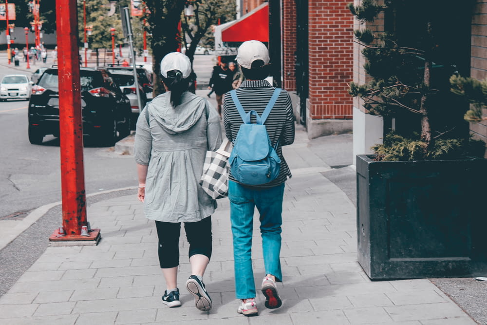 2 person wearing mask standing on sidewalk during daytime