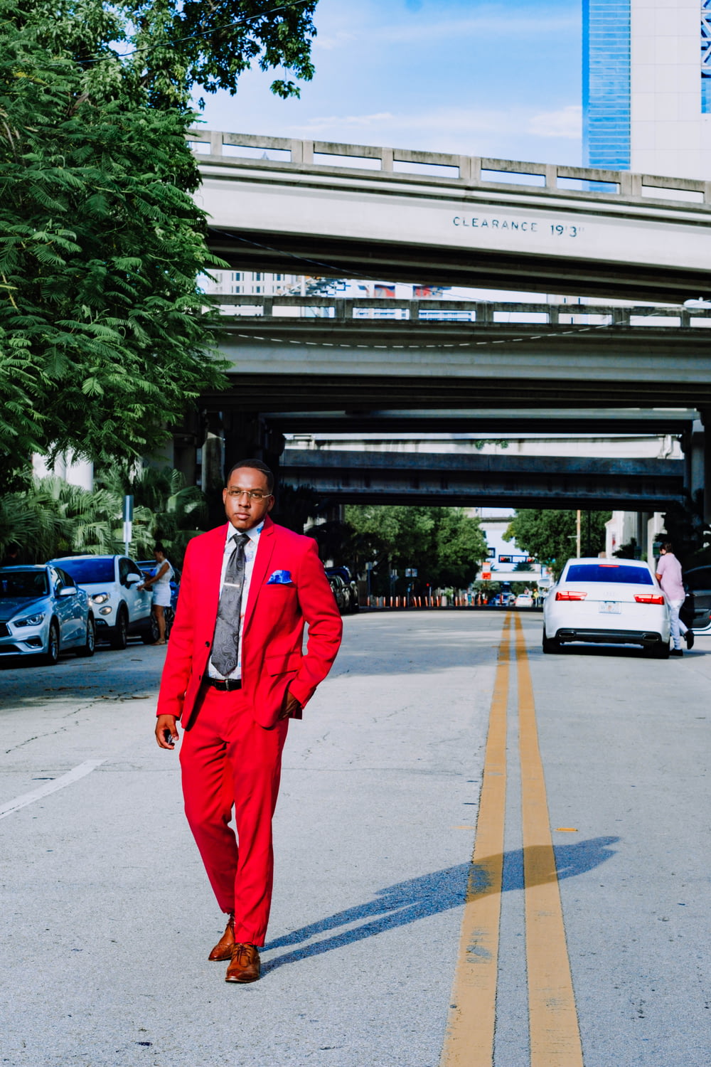 man in red suit standing on sidewalk during daytime