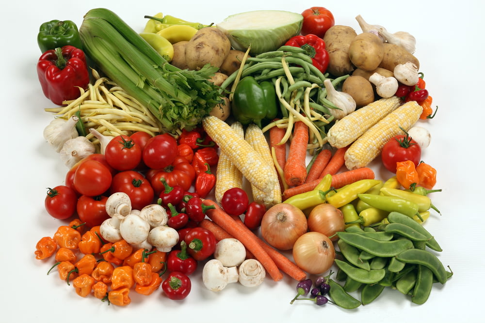 un tas de différents types de légumes sur une surface blanche