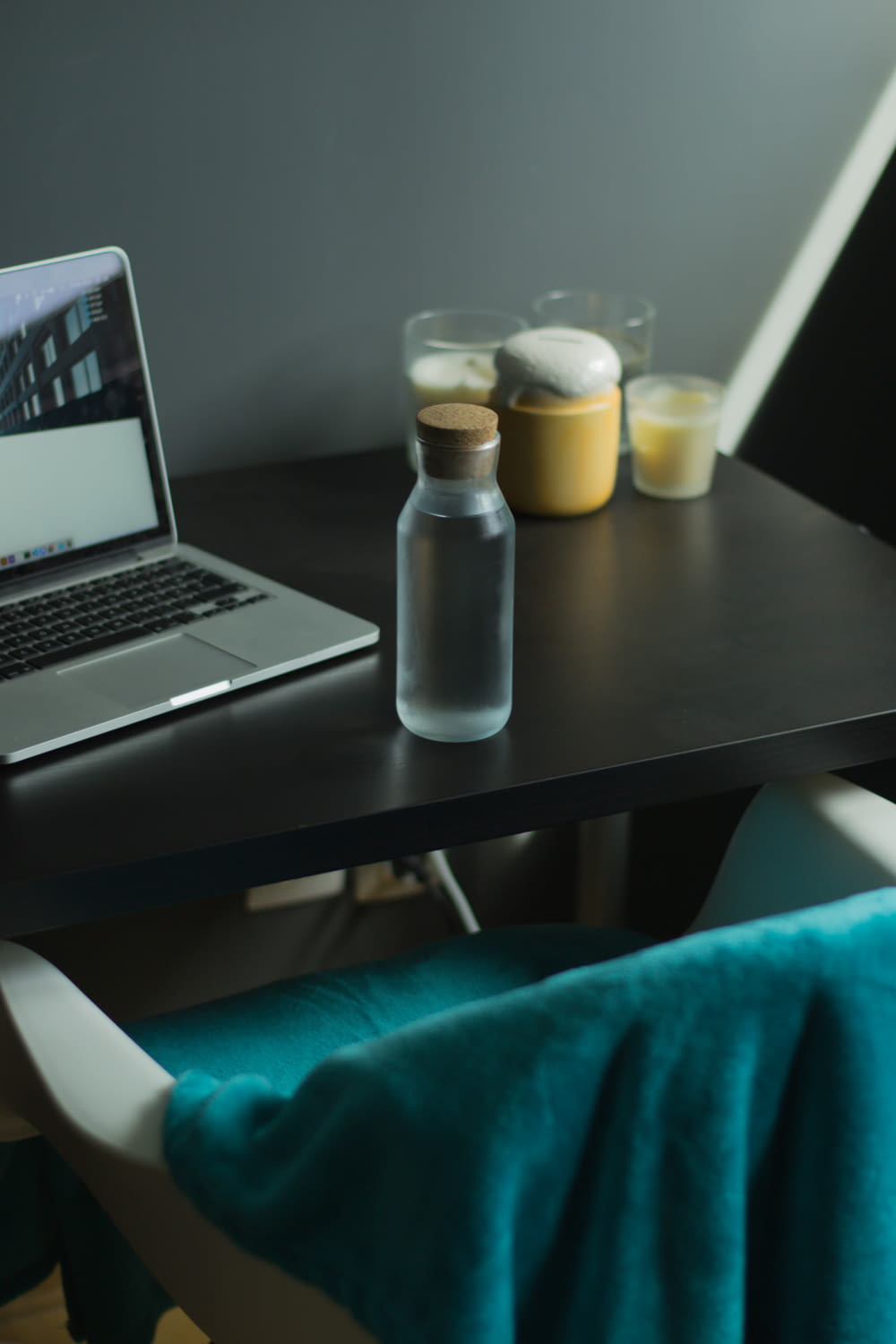 clear plastic bottle beside black laptop computer on black wooden table