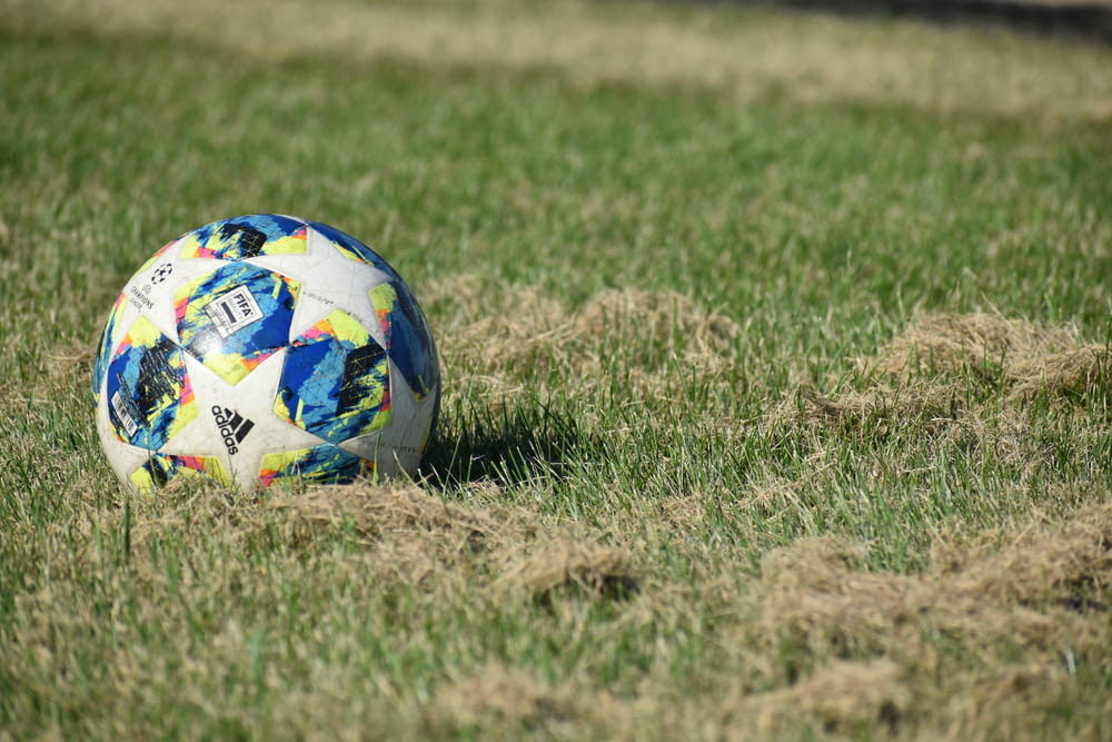 blue white and red soccer ball on green grass field during daytime