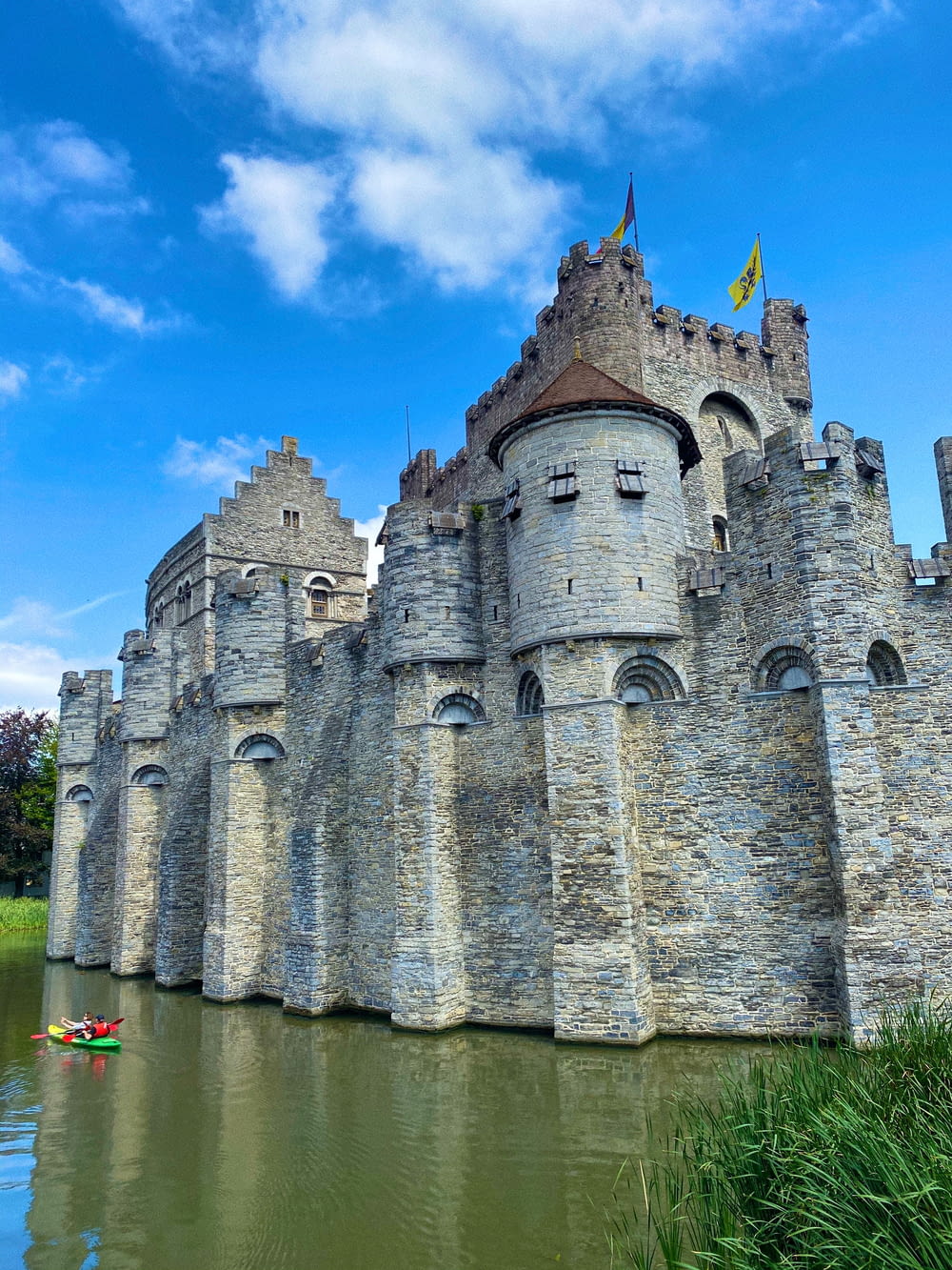 grey concrete castle near body of water under blue sky during daytime