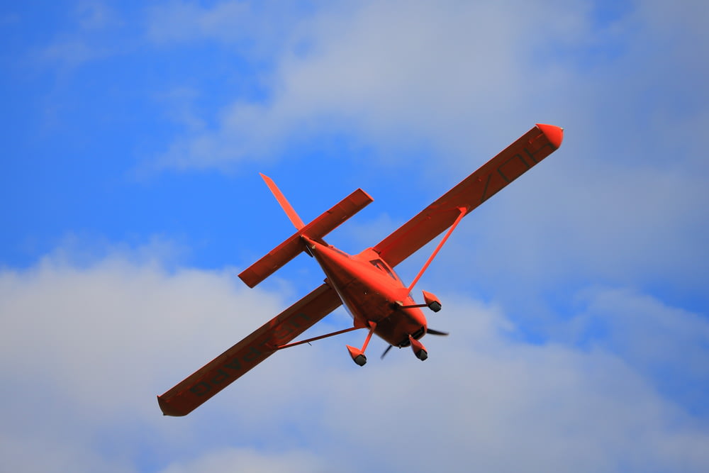 red plane in mid air during daytime