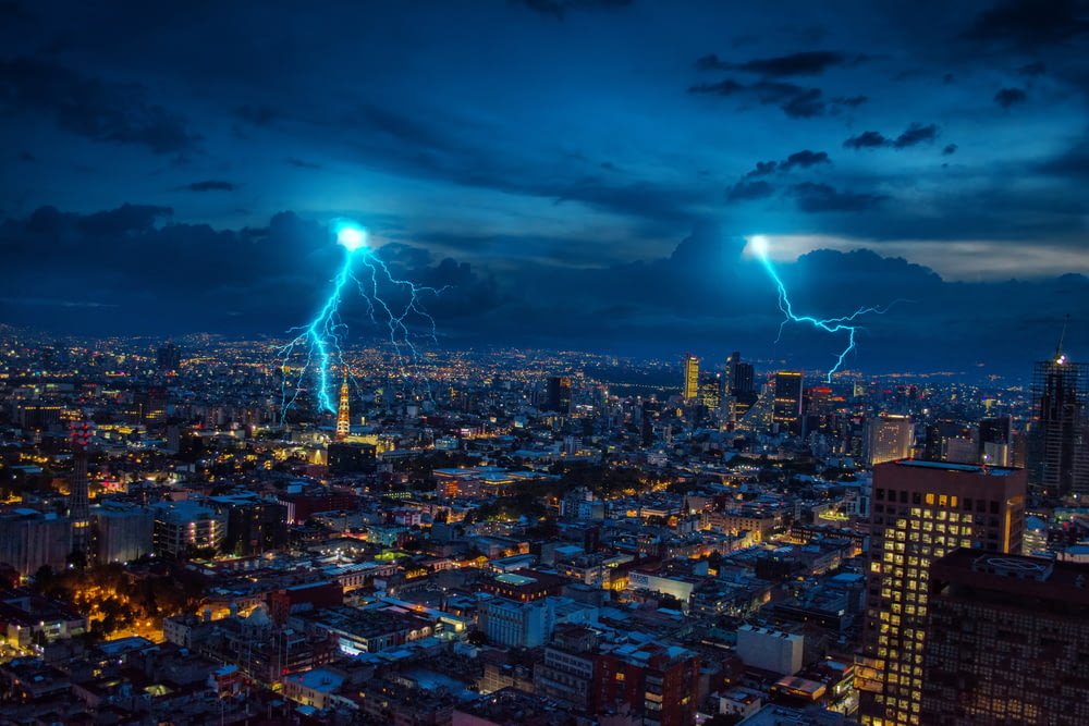 city with high rise buildings under blue sky with lightning during nighttime