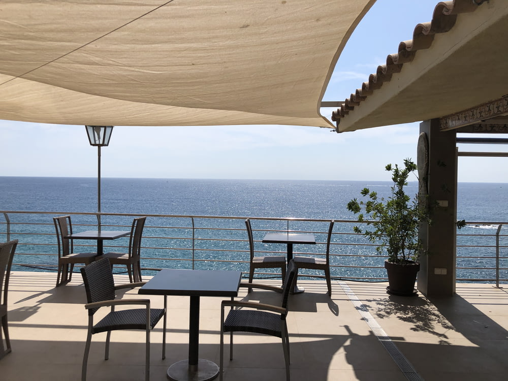 brown wooden table and chairs near sea during daytime