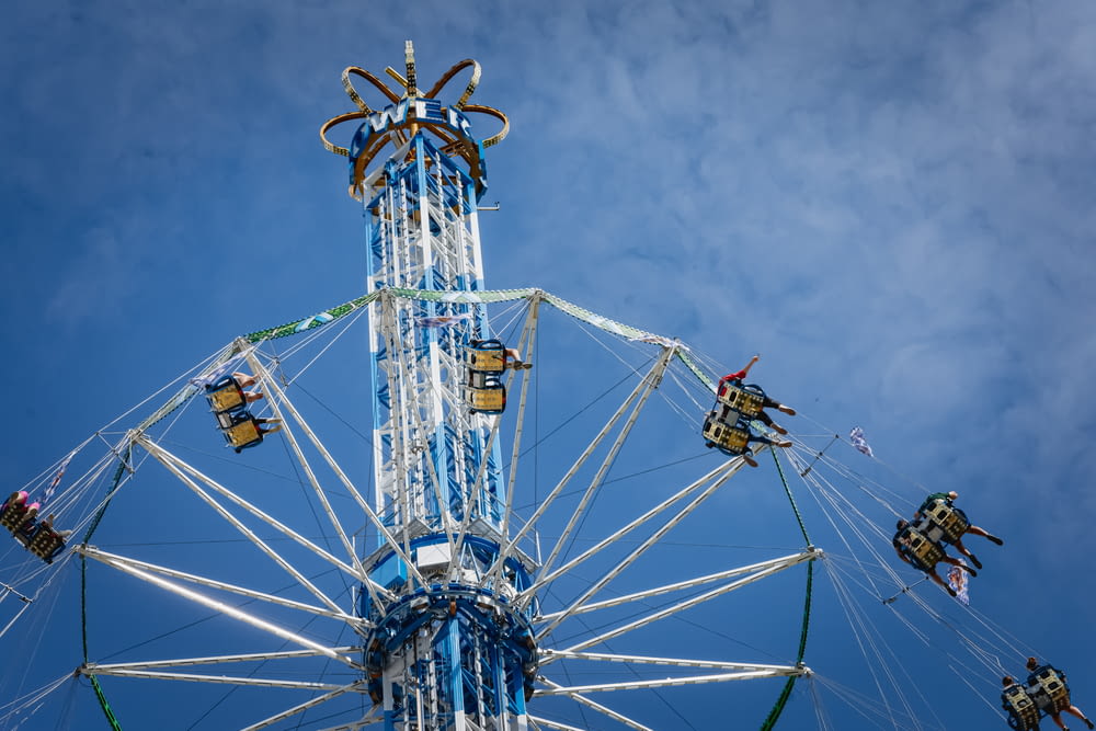 people riding on white and blue ferris wheel under blue sky during daytime