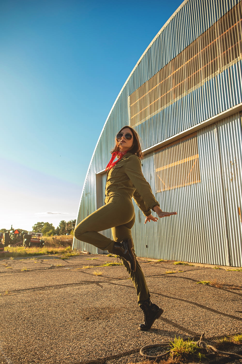 woman in green jacket and black pants jumping on brown field during daytime