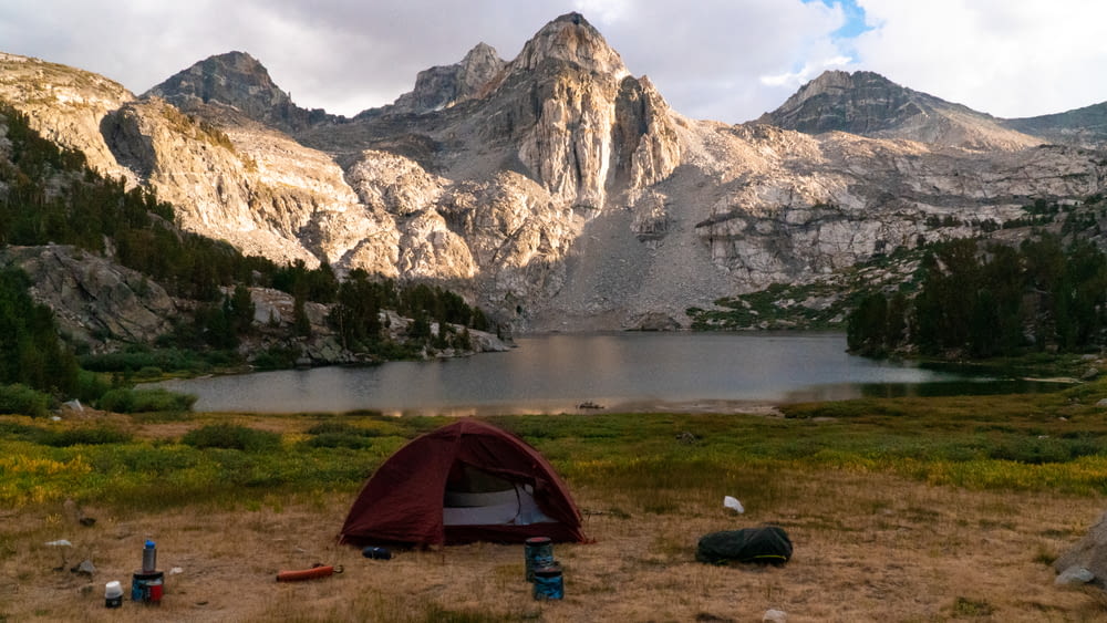 tenda grigia e nera vicino al lago e alla montagna