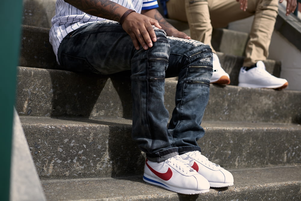 Persona in jeans blu denim e scarpe da ginnastica Nike bianche