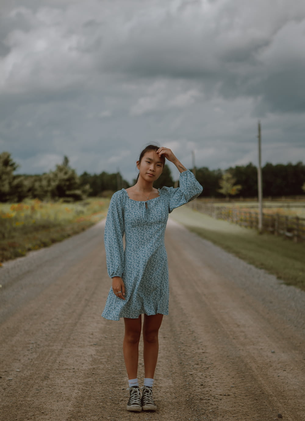woman in blue long sleeve dress standing on road during daytime