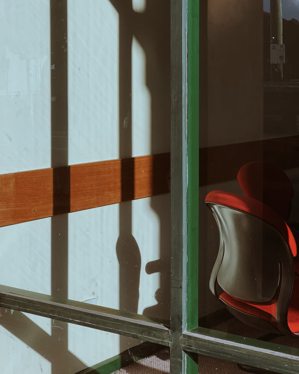 sedia rossa e nera accanto alla finestra di vetro