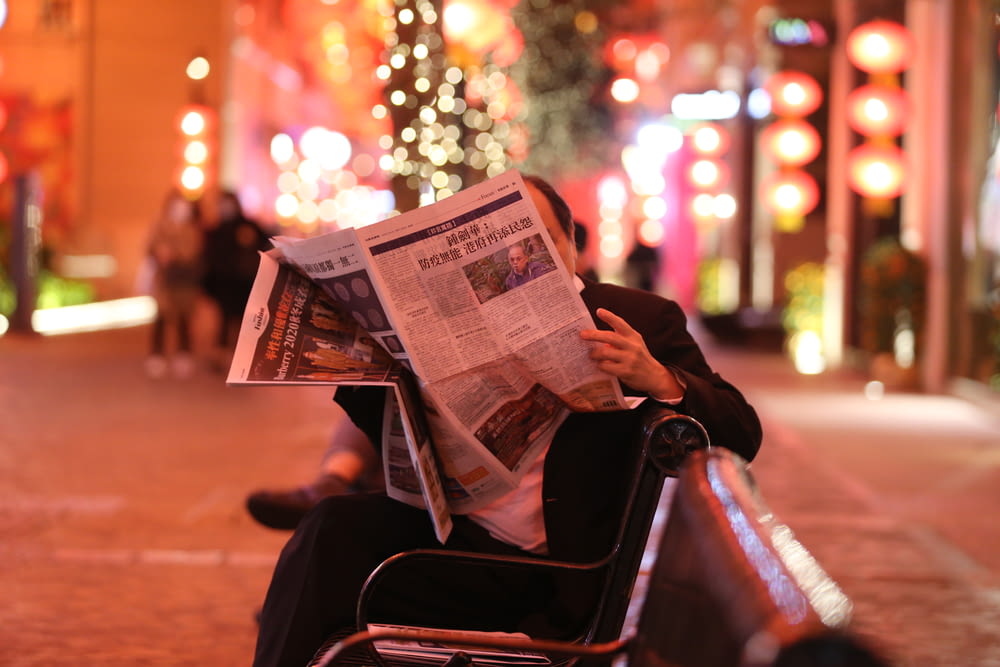 person reading newspaper sitting on chair