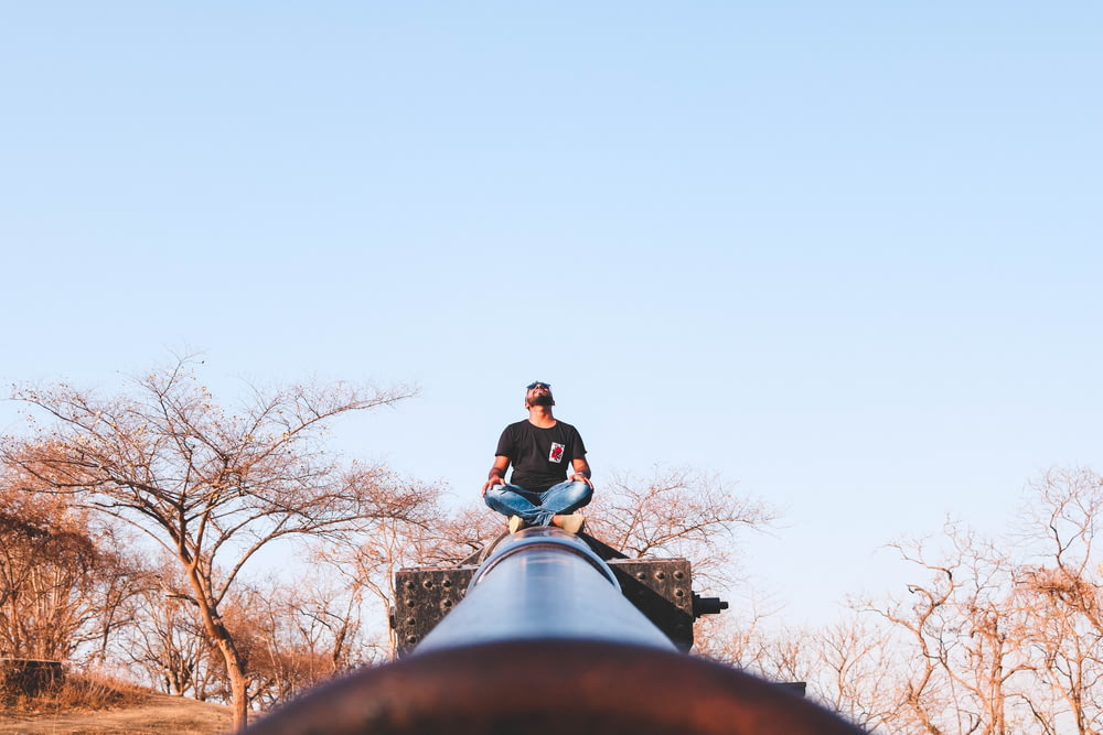 a man sitting on top of a metal pipe