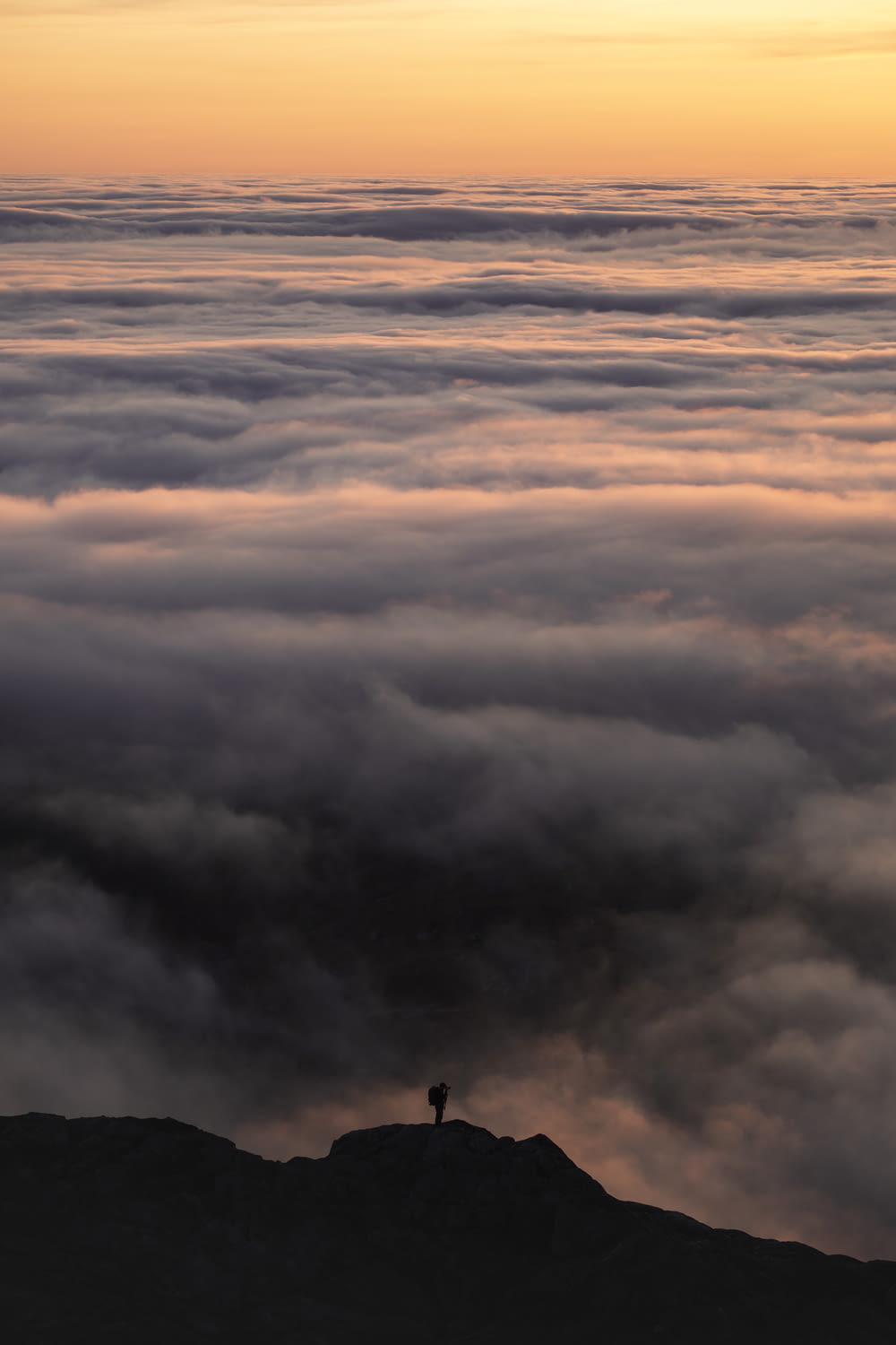 person standing on top of the mountain under white clouds