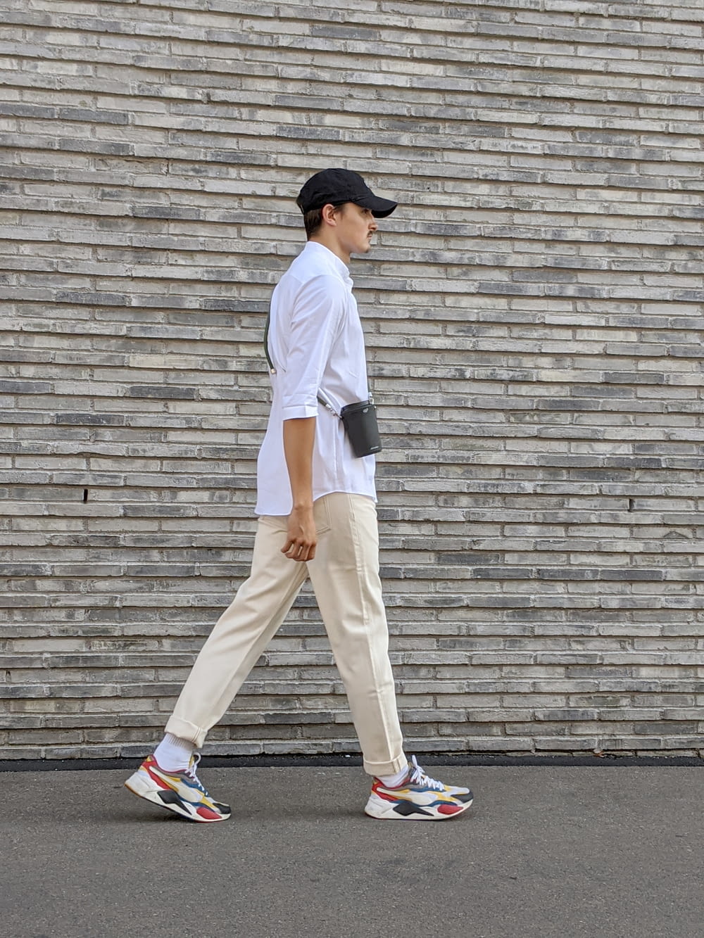 man in white t-shirt and beige pants standing on gray concrete floor