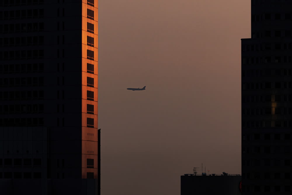 a plane is flying in the sky near tall buildings