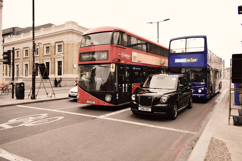 낮 동안 빨간 버스 근처 도로에서 검은 색과 빨간색 버스