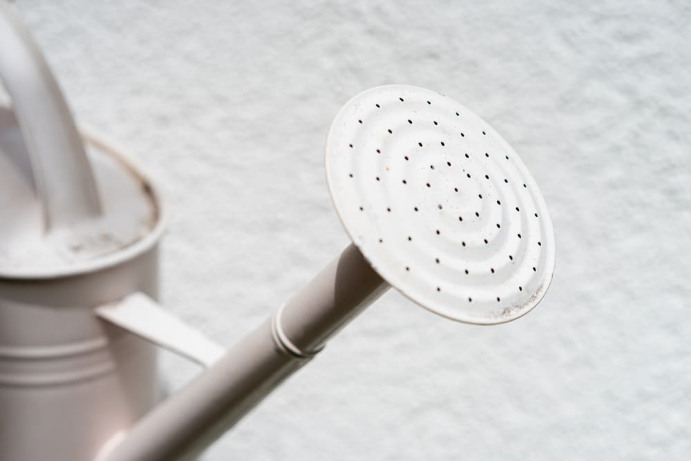 a close up of a white shower head on a white wall