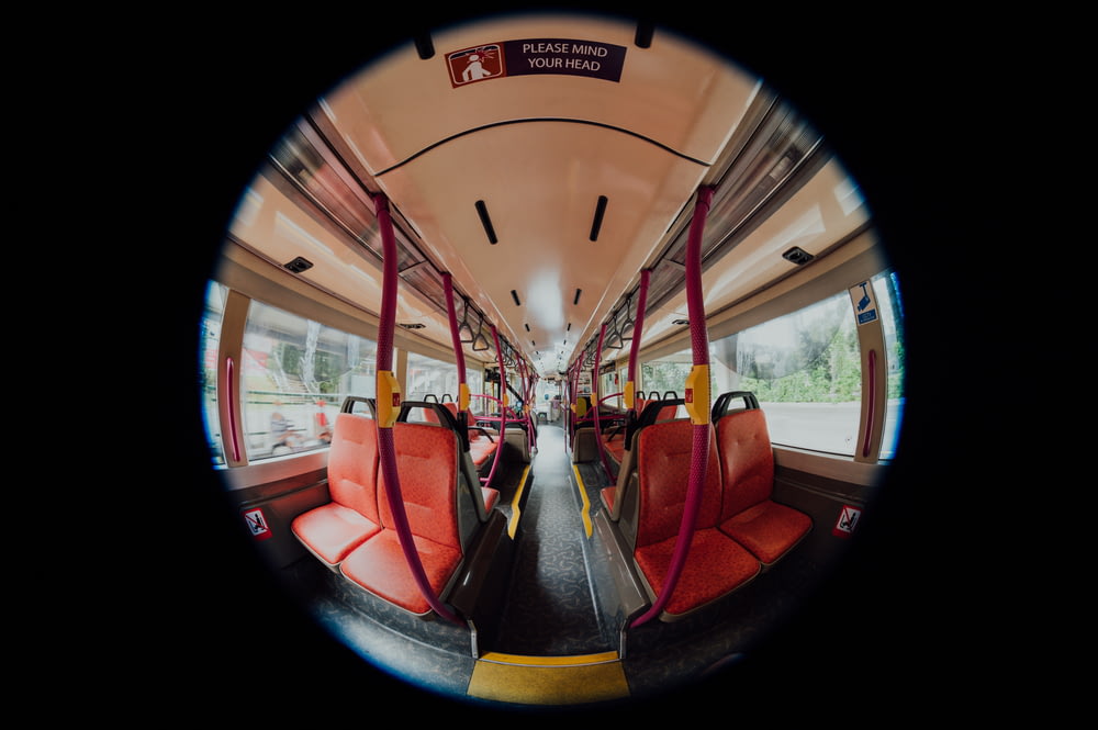 uma vista do interior de um ônibus com assentos vermelhos