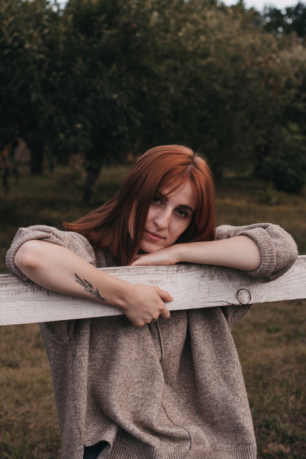 woman in gray sweater lying on brown wooden bench