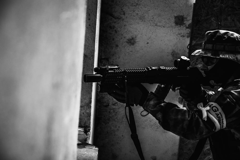 foto em escala de cinza da pessoa segurando o rifle