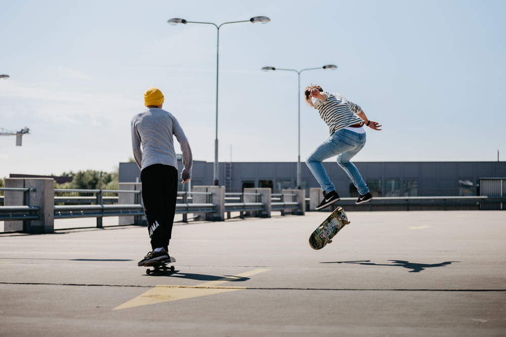白いシャツと黒いズボンを着た男性が昼間、スケートボードをしている