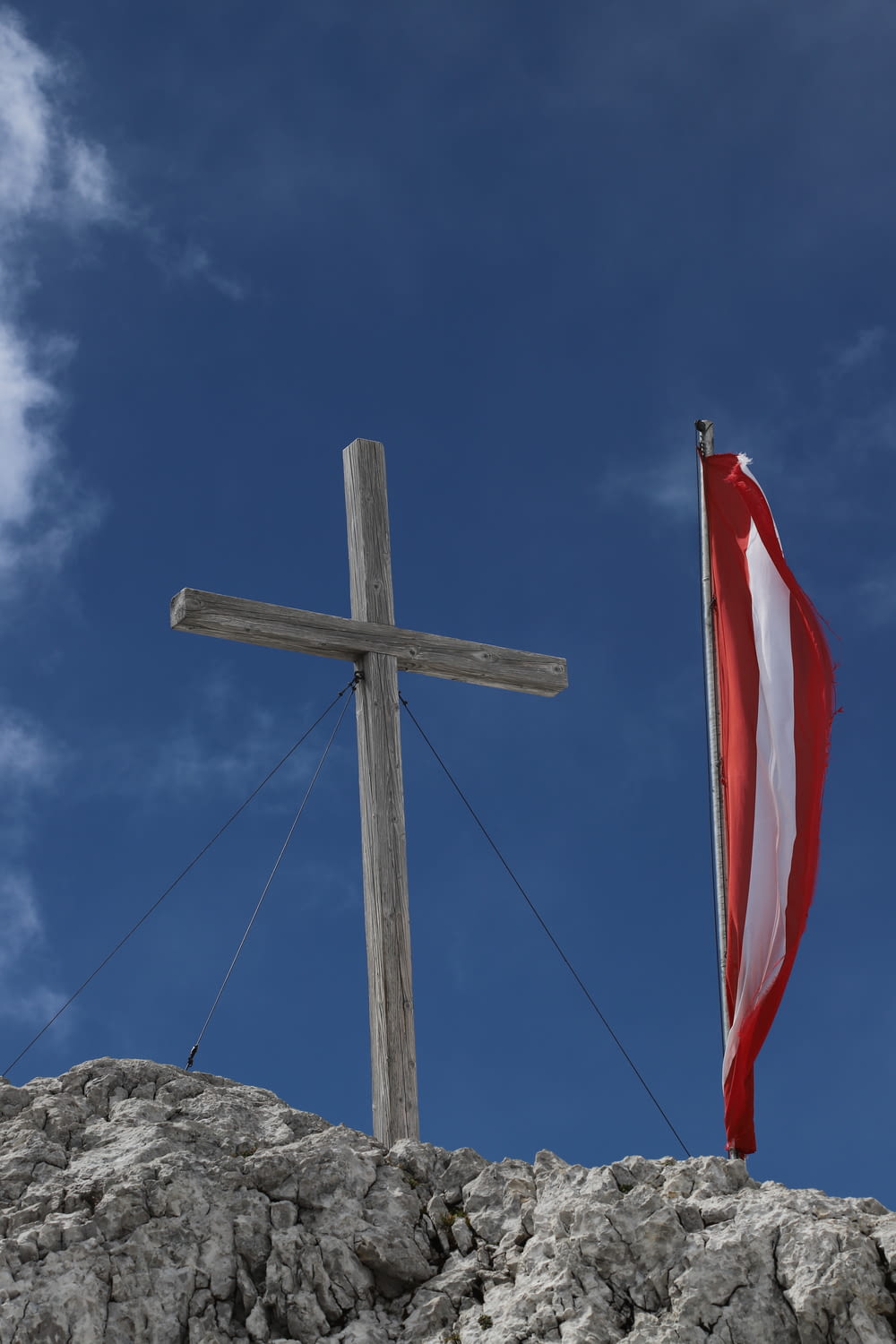 brown wooden cross with red flag on top of brown rock