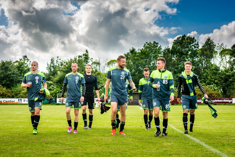 Gruppo di uomini in camicia verde della maglia di calcio sul campo di erba verde