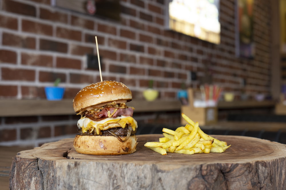 burger with fries on brown wooden chopping board