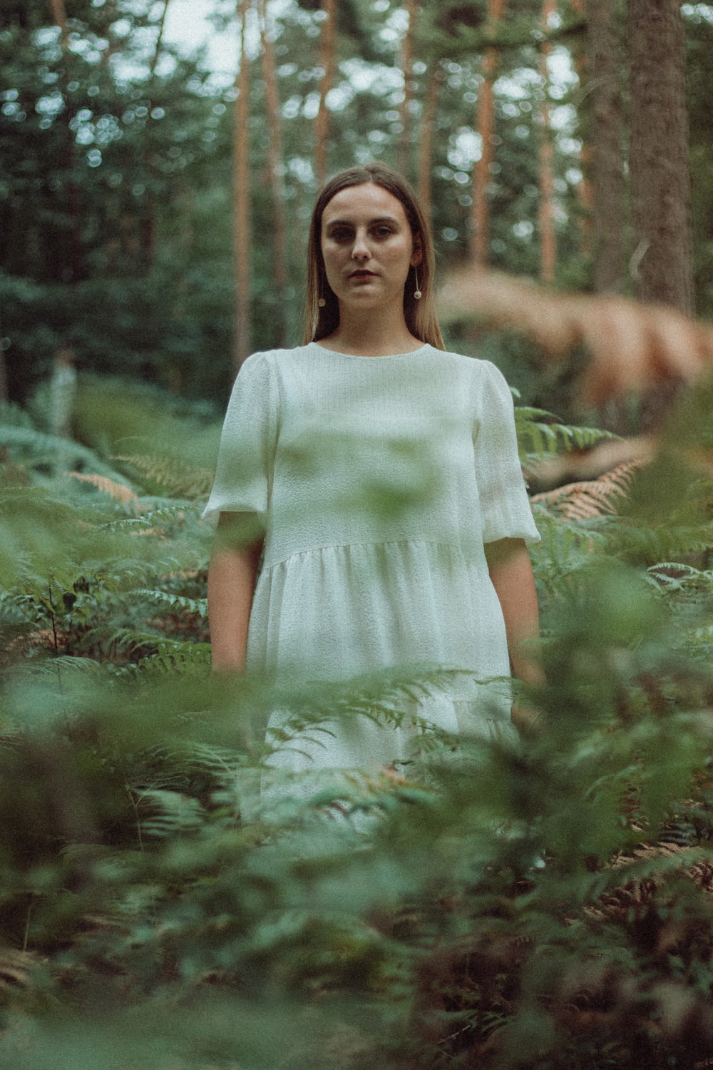 woman in white dress standing in the woods