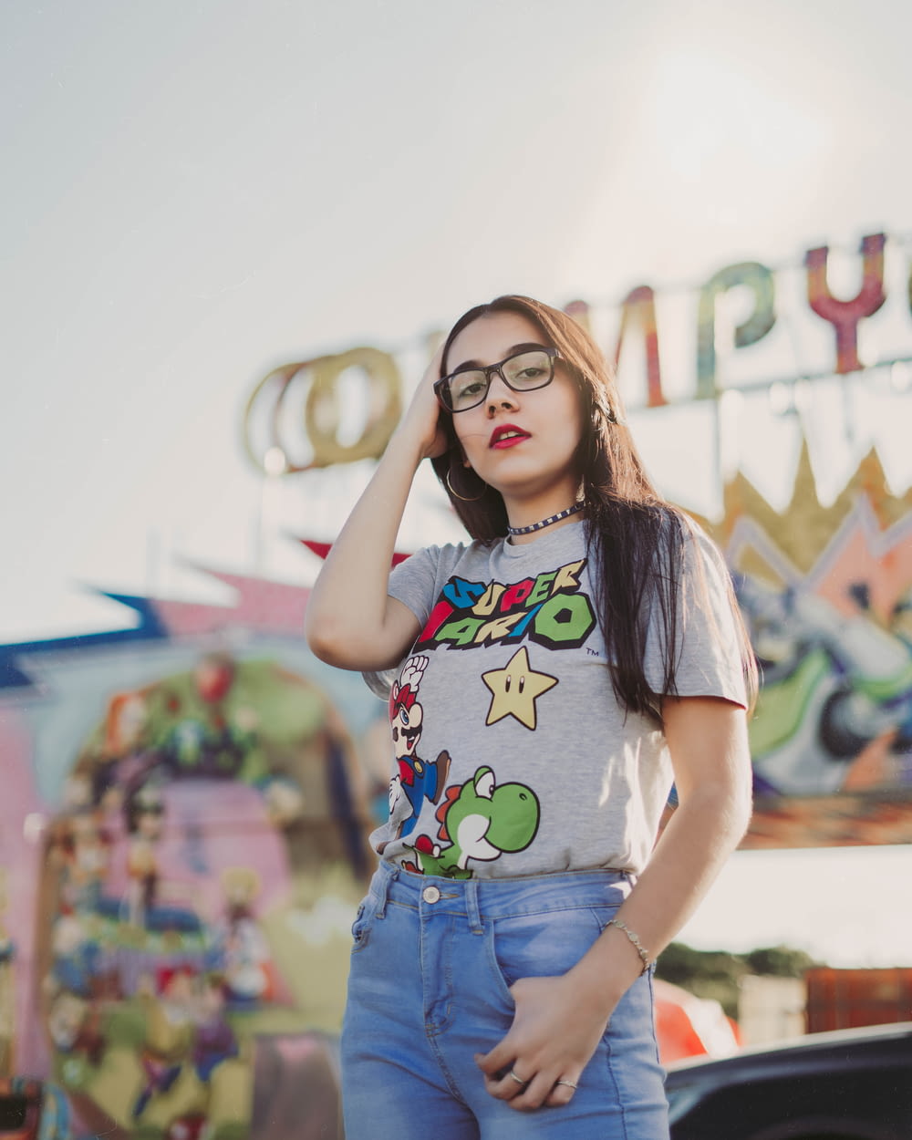 a woman wearing glasses standing in front of a carnival ride