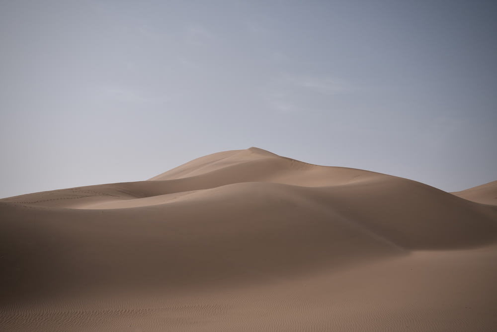 昼間の白い空の下の茶色の砂漠