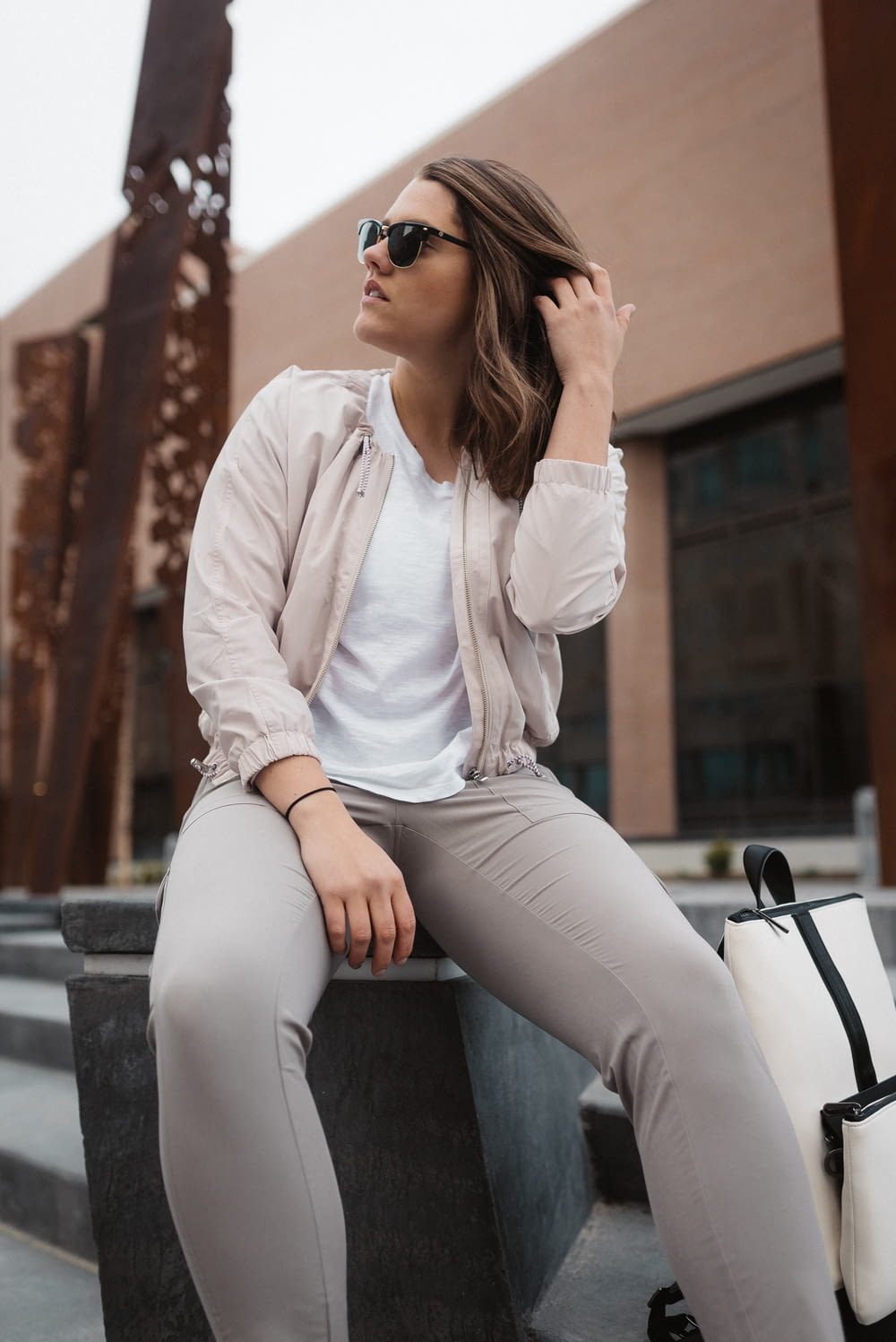 woman in white long sleeve shirt and gray pants sitting on gray concrete bench during daytime