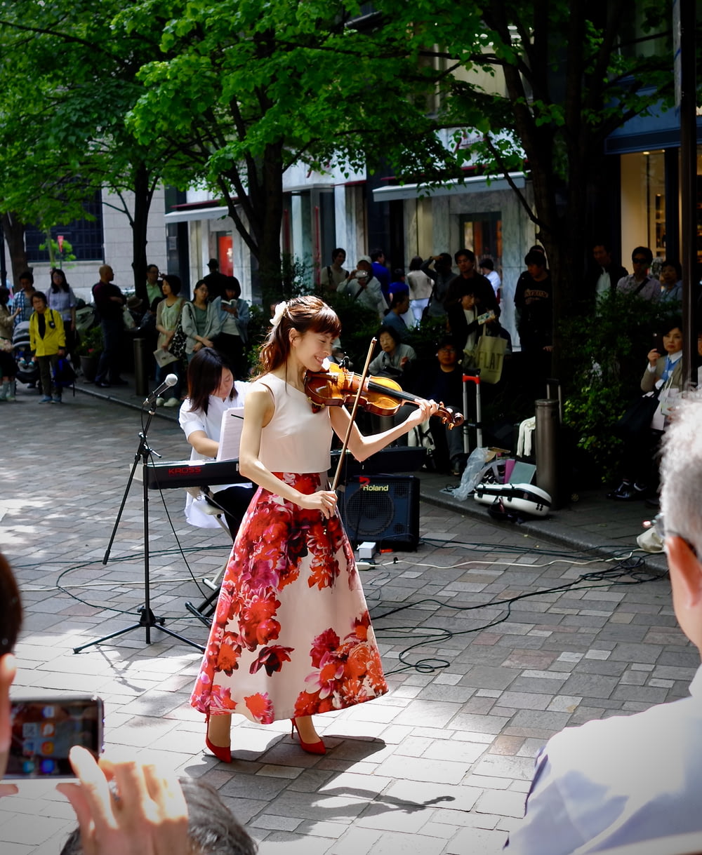 mujer con vestido floral rojo y blanco tocando el violín
