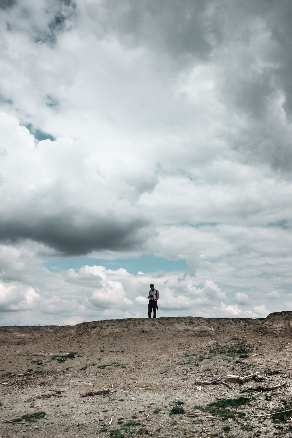 Persona parada en un campo marrón bajo nubes blancas durante el día