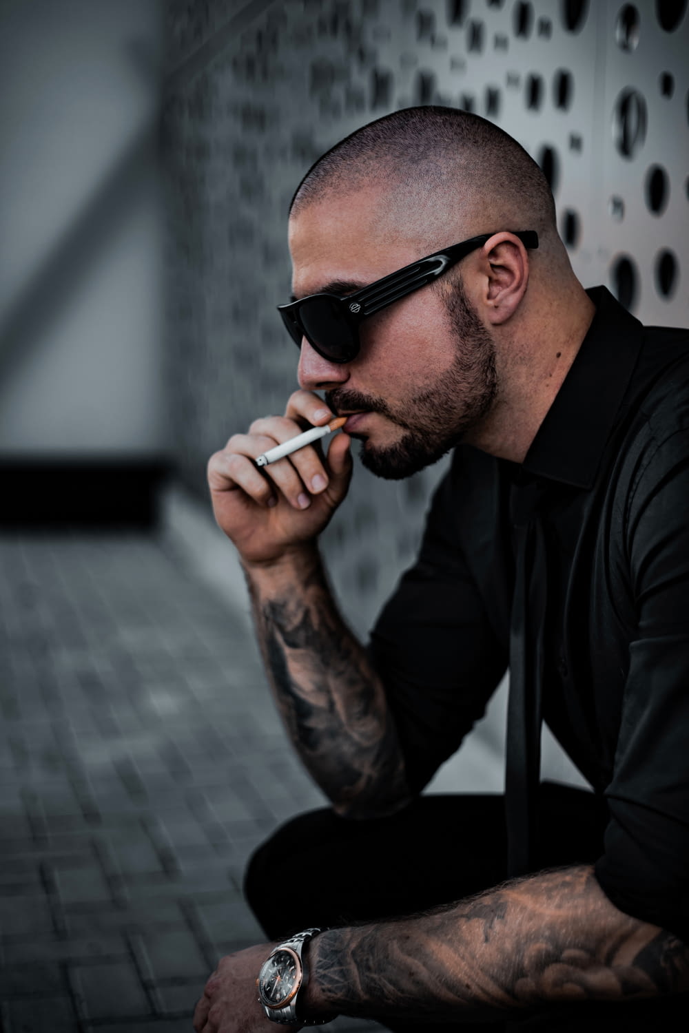 uomo in camicia nera che fuma sigaretta