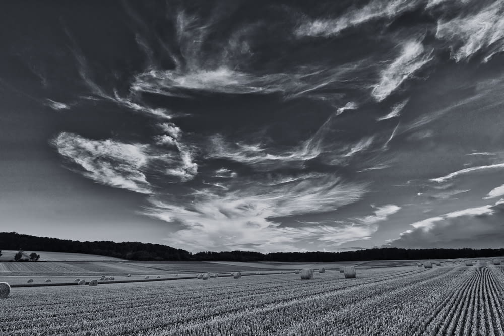 foto em tons de cinza de um céu nublado sobre o campo