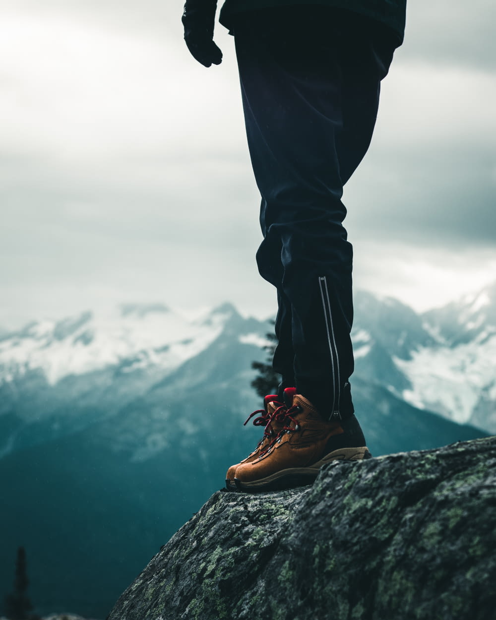 person in black pants and brown leather boots standing on rock during daytime