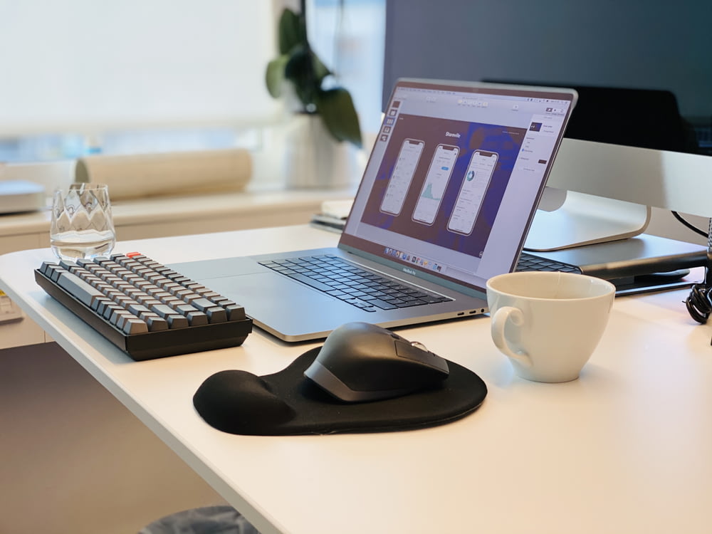 맥북 프로 옆에 검은 컴퓨터 마우스와 검은 컴퓨터 키보드 흰색 테이블