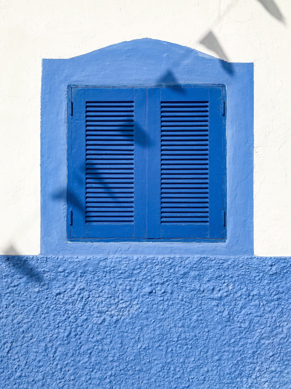 blue wooden window on white concrete wall