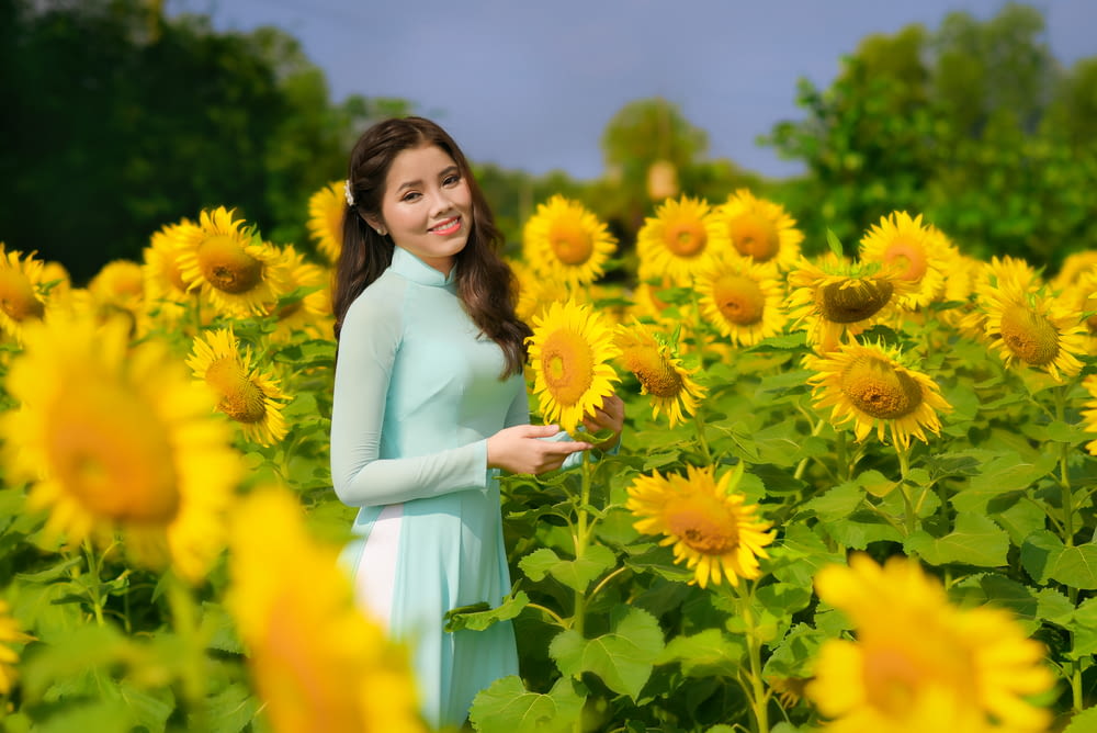 woman in white dress standing on yellow flower field during daytime