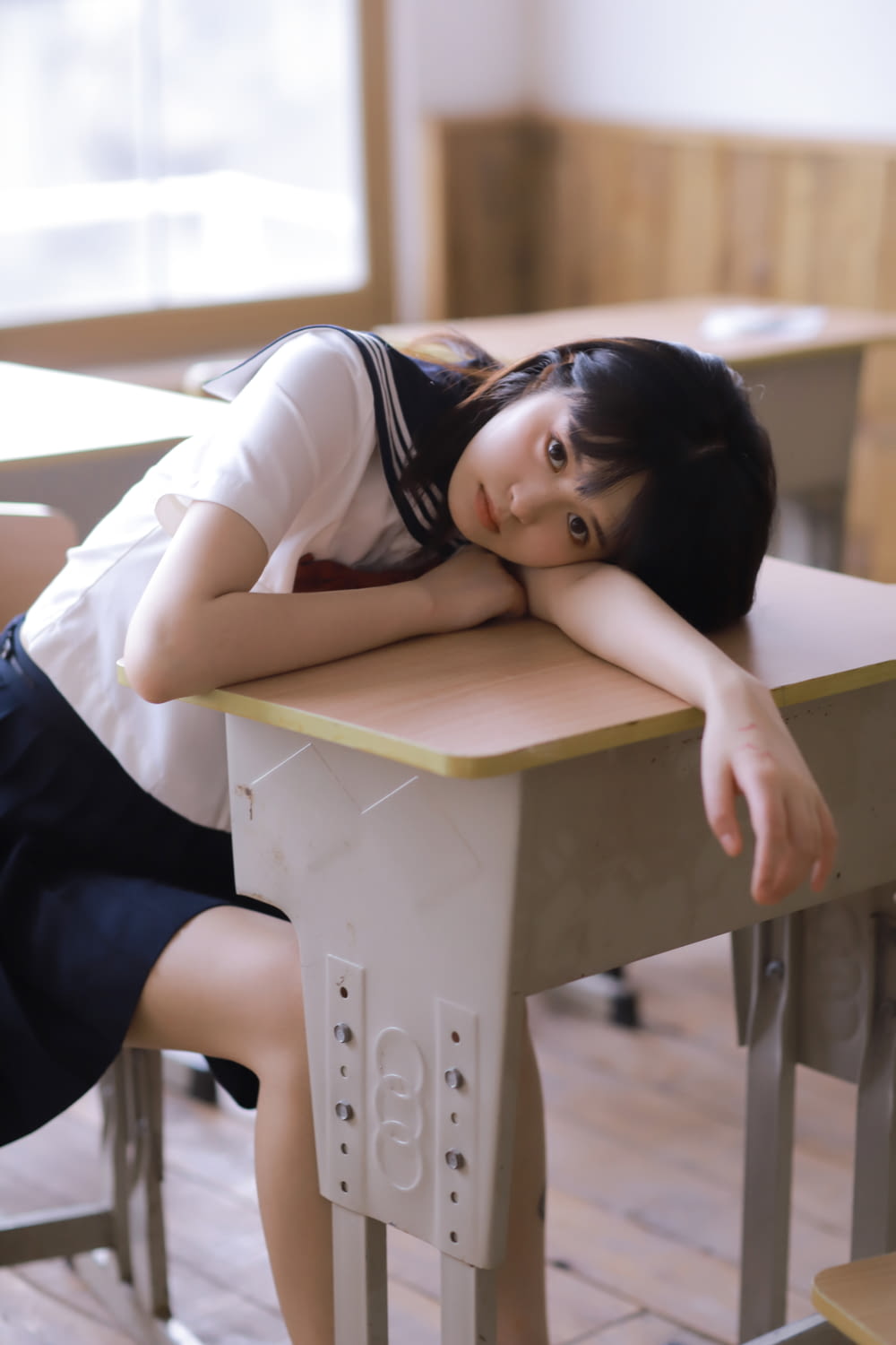 girl in white t-shirt and black skirt lying on brown wooden table