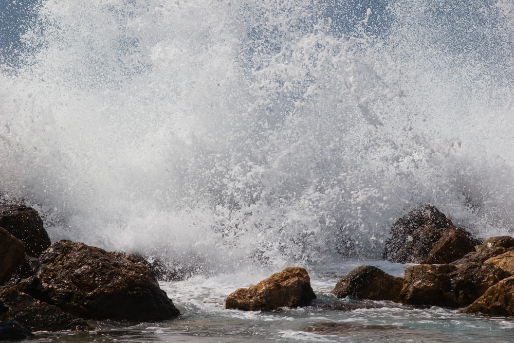 water waves hitting brown rocks