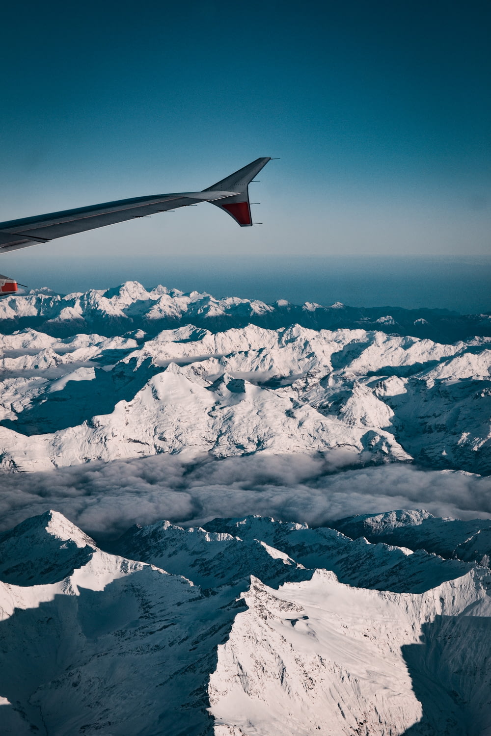 Rot-weißer Flugzeugflügel über schneebedecktem Berg