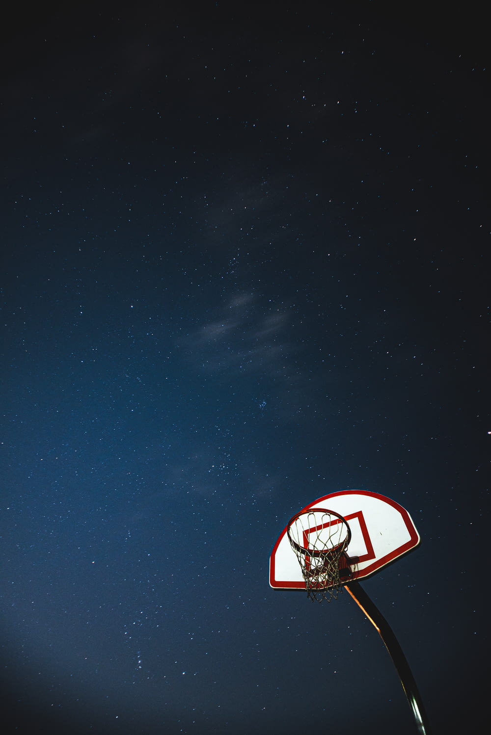 white and red basketball hoop under blue sky